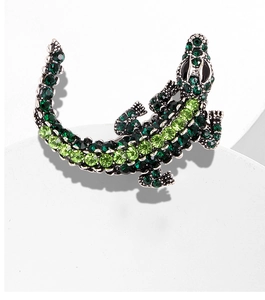 Close-up of green rhinestone encrusted crocodile brooch with detailed silver plating
