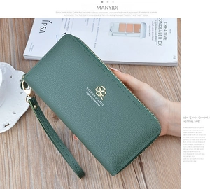 Macro view of green litchi texture leather wallet with gold clover and wrist strap