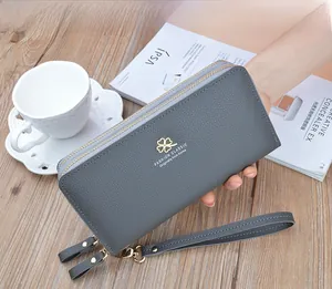 Close-up of litchi texture on grey double zipper wallet with a clover metal logo