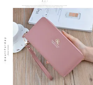 Pink double-zipper wallet with lychee texture and clover logo on a wooden surface