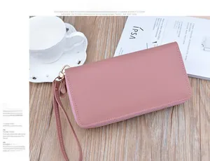 Detail of pink long wallet with litchi texture and golden zipper with wrist strap