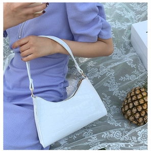 Close-up of white crocodile pattern hobo bag with gold hardware and zipper detail