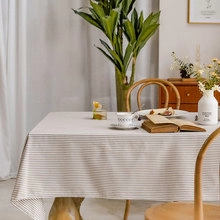 Detailed view of beige striped tablecloth with elegant tassels on a wooden dining table