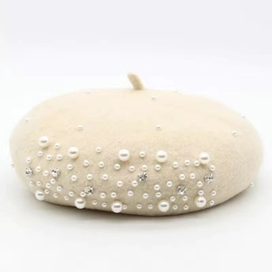 Detailed view of beige wool beret featuring elegant pearl and rhinestone embellishments