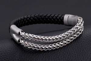 Detail of double stainless steel wheat chains joined with black woven leather cord