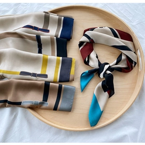 Detailed view of geometric silk scarves on a wooden tray with elegant folding patterns