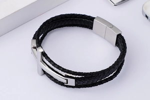 Macro detail of men's multilayer braided leather bracelet with silver steel cross and magnetic clasp