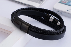 Détail d'un bracelet multicouche en cuir noir avec corde tressée et fermoir magnétique noir