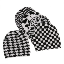 Detail view of five knitted beanie hats with leopard, cow, and checkerboard patterns