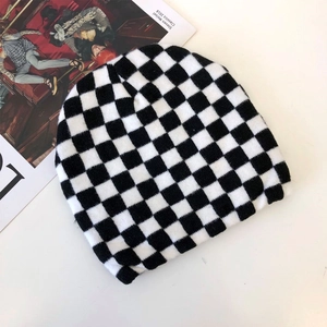 Detail of black and white checkerboard knit beanie with magazine as fashion prop