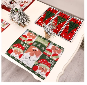 Flat lay of Christmas placemats with Santa and tree motifs on white wooden table