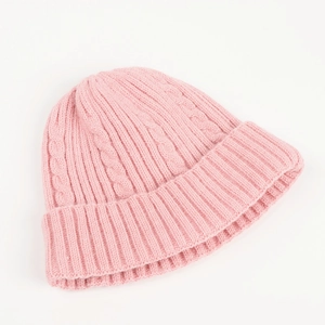 Detailed close-up of pink cable knit texture and folded cuff on a warm winter beanie