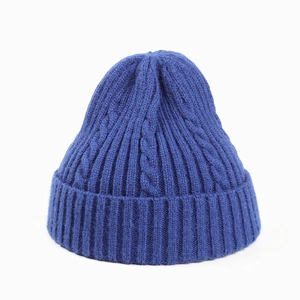 Detailed close-up of blue cable knit beanie with thick ribbed cuff and woven texture