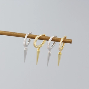 Detailed view of silver and gold geometric rivet earrings hanging on a minimal wood branch