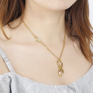 Gold infinity necklace set with a hollow heart charm shown on a model's neckline