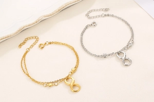 Detail showing gold and silver infinity bracelets with heart charms on soft fabric