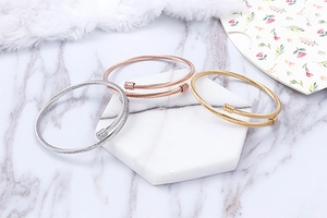 Three-color cable wire bangle set in silver, gold, and rose gold on marble