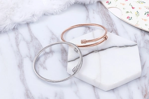 Detail of silver and rose gold cable wire bangles on elegant marble and stone surfaces