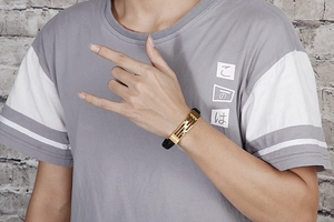 Detail of a braided leather bracelet with gold metal clasp worn on a male wrist