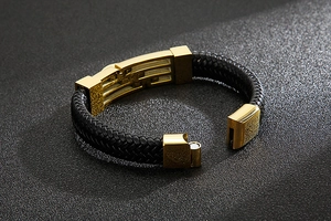 Detailed view of black braided leather bracelet with a polished gold stainless steel clasp