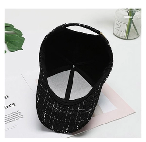 Detail of black tweed baseball cap featuring interior lining and adjustable metal buckle