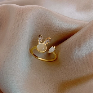 Détail de la bague ouverte lapin et carotte plaquée or sur un tissu en soie champagne