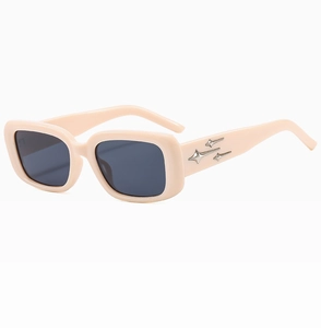 Dettaglio degli occhiali da sole beige con accenti metallici a stella sulla stanghetta