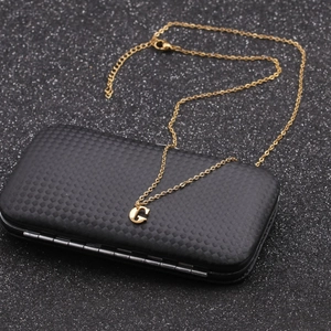 Macro shot of gold-plated necklace with a G letter pendant on a black textured box