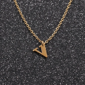 Close-up of a gold V-shaped letter pendant on a delicate chain against a dark background
