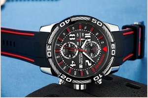Macro detail of chronograph watch dial with steel cable bezel and red silicone strap