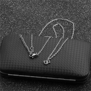 Close-up of silver chain necklace featuring a bold letter S pendant on a dark texture