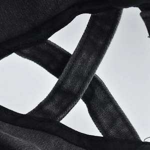 Détail du tissu en coton délavé noir avec un design à lanières croisées sur la casquette de baseball