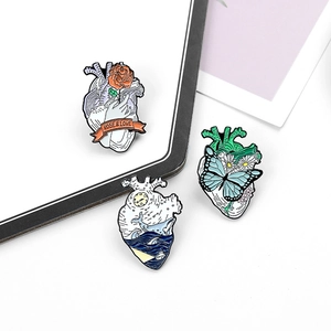 Detailed view of anatomical heart enamel pins featuring whale waves and floral patterns