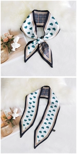 Detail of white heart pattern narrow silk scarf on plush background with elegant props