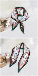 Detail of green edged silk scarf featuring elegant bird and floral prints on satin fabric