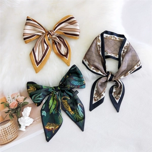 Three elegant silk scarfs with leopard and chain prints on a soft white fur background