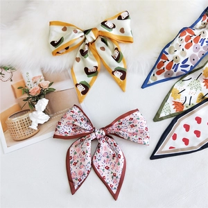 Narrow silk scarves with heart and floral prints tied in elegant bows for women