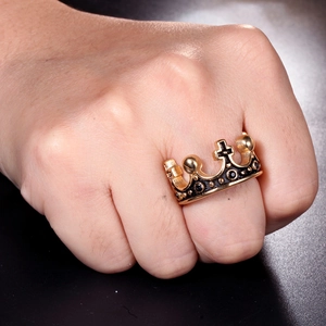 Detail of a gold crown ring with black gemstones and cross on a person's finger