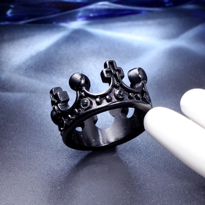 Detailed view of a black crown steel ring with cross motifs on a dark textured surface