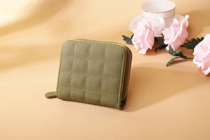 Detail of olive green quilted zip wallet with textured faux leather on a cozy table