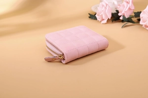 Macro view of pink quilted leather texture and gold zipper on mini wallet