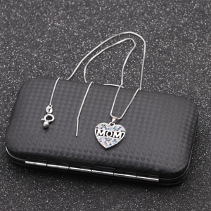 Close-up of MOM heart pendant necklace with colorful zircons on a textured black box
