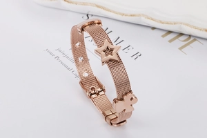 Dettaglio del bracciale a maglia oro rosa con ciondoli a stella e orso e fibbia regolabile