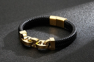Macro shot of a braided black leather men's bracelet with a golden metal buckle