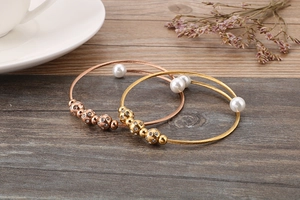 Detail of rose gold and gold steel wire bracelets with pearls and sparkling rhinestones