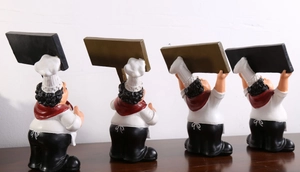 Rückansicht von vier kreativen Harz-Chef-Figuren mit Menütafeln auf einem Holztisch