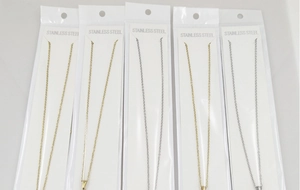 Detail of stainless steel letter necklaces in bulk packaging with golden and silver finishes