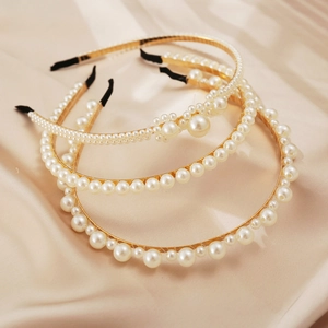 Detailed view of three elegant faux pearl headbands with gold alloy on champagne silk