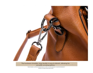 Detailed close-up of gunmetal shoulder strap buckle on textured brown leather handbag