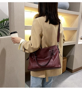 Detail showing the burgundy pebbled leather texture and adjustable strap of the shoulder bag